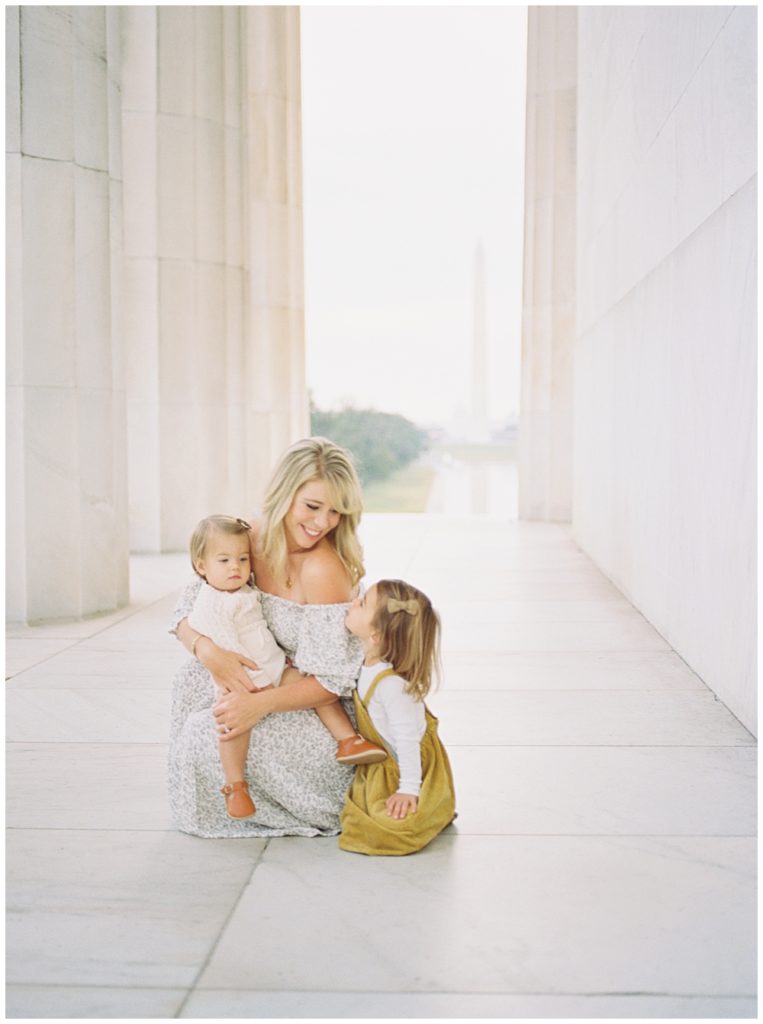Mother smiles at her daughters while sitting in the Lincoln Memorial