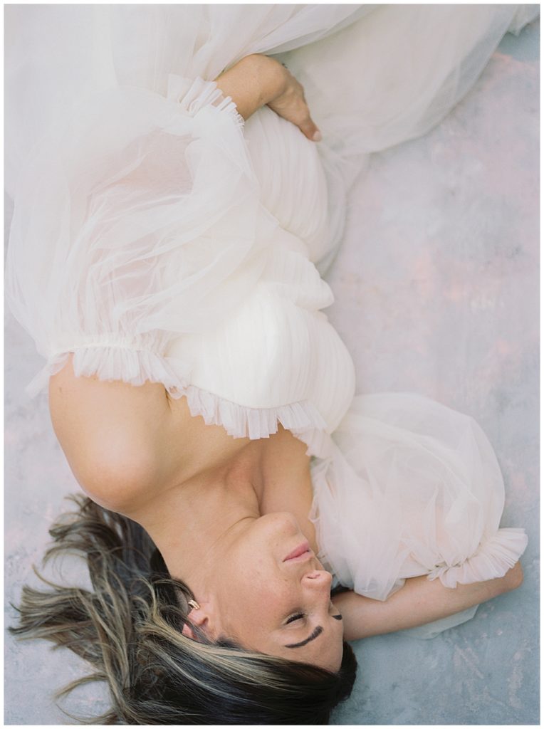 Pregnant mother lays down with a hand on her belly during her DC studio maternity session
