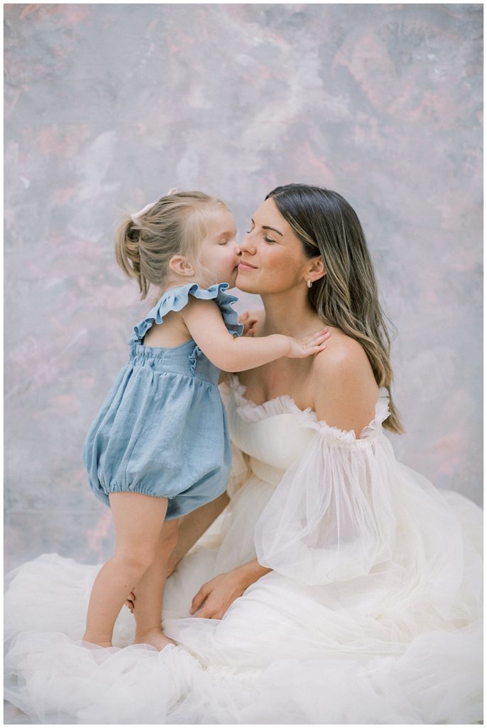 Little girl kisses her mother's cheek during their DC studio motherhood session