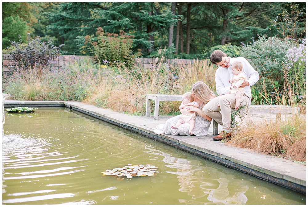 Family sits on the edge of a pond at Brookside Gardens