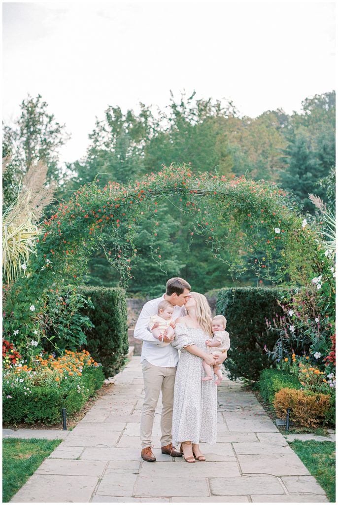 Mother and father kissing while holding their twin babies at Brookside Gardens