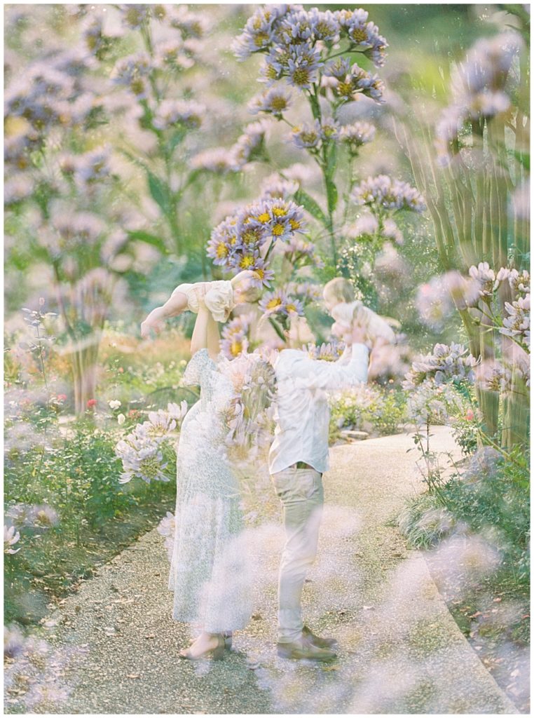 Double exposure of mother and father holding their children and purple flowers