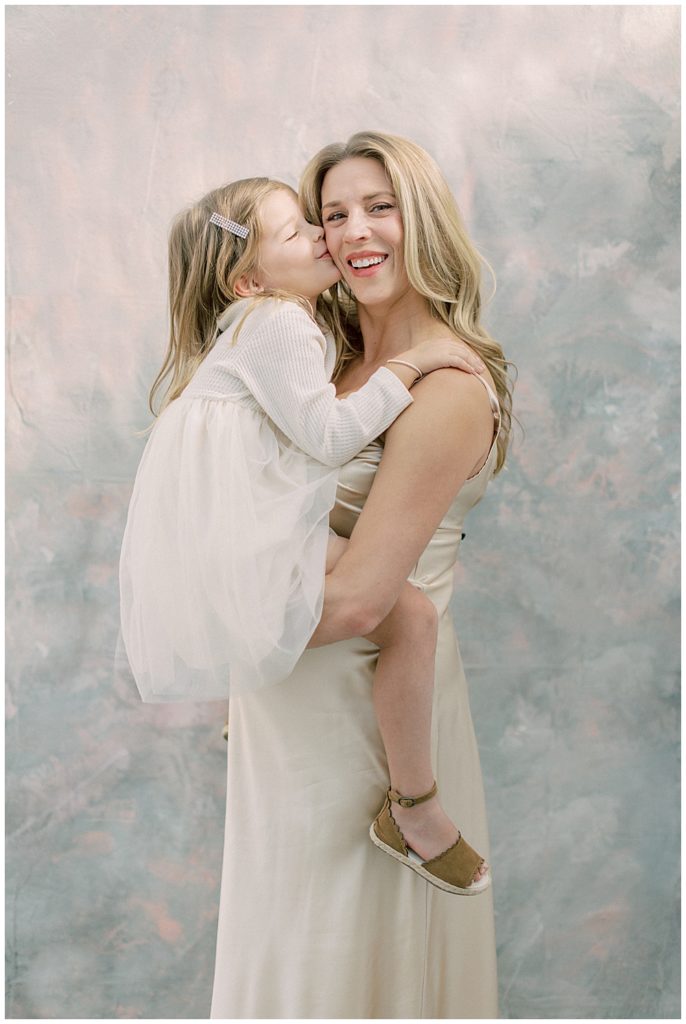Little girl kisses her pregnant mother during their maternity session