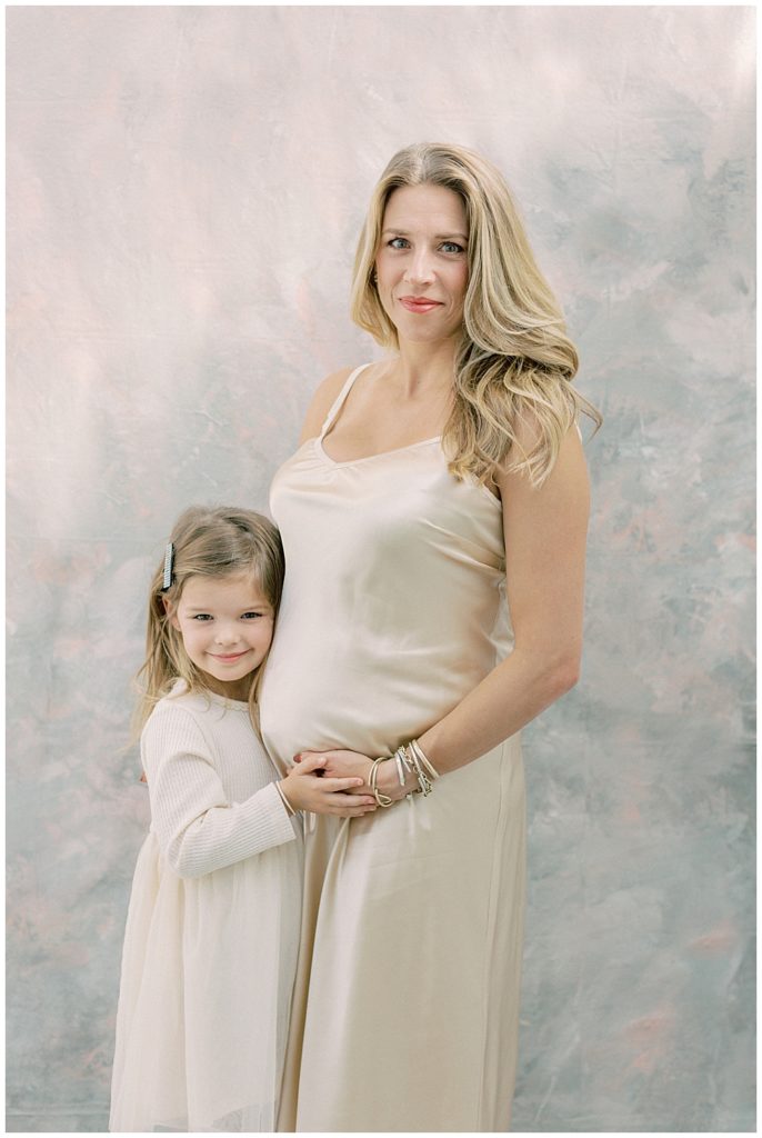 Pregnant mother and young daughter embrace during a studio maternity session