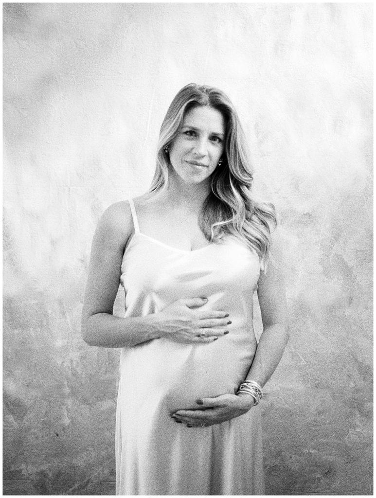 Black and white image of mother looking at the camera while holding her pregnant belly