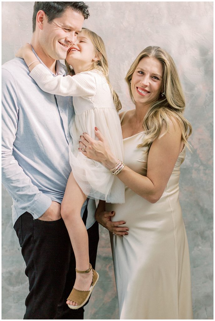 Parents embrace their little girl during their maternity session in a studio