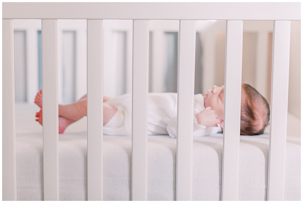 A newborn baby lays in her white crib in Arlington VA during her newborn session