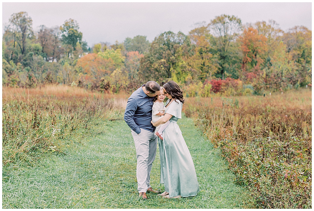 Mother and father hold their toddler daughter and lean into her at the Howard County Conservancy during their family photo session by Maryland Family Photographer Marie Elizabeth Photography