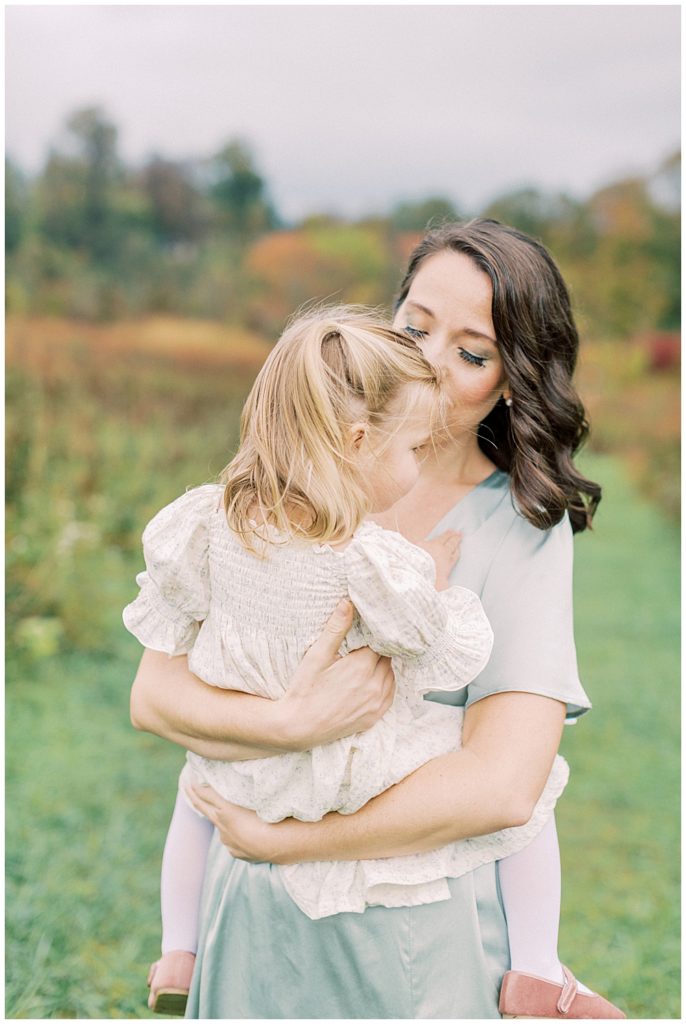 Mother leans into her young daughter as she holds her during her family photo session at the Howard County Conservancy