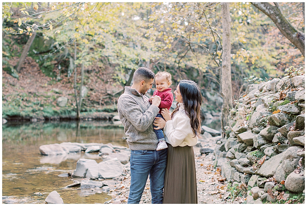 Mother, father, and baby stand together by a creek during their Washington DC family photo session