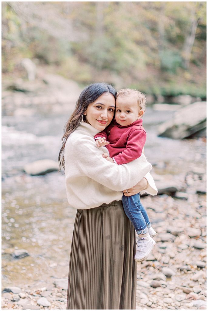 Mother holds her baby boy up close to her while standing near a creek in Washington DC