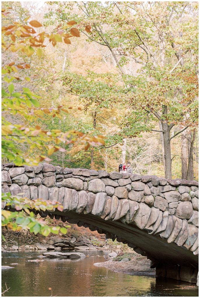A family stands on Boulder Bridge in Rock Creek Park in DC during their family photo session