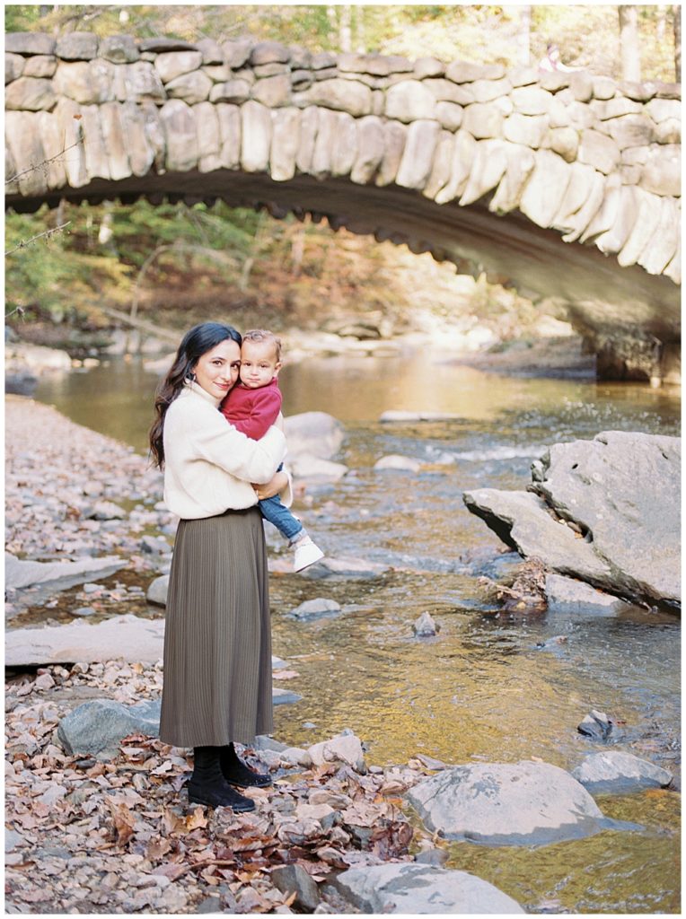 Mother holds her infant son up close to her during her fall family session in Rock Creek Park in DC