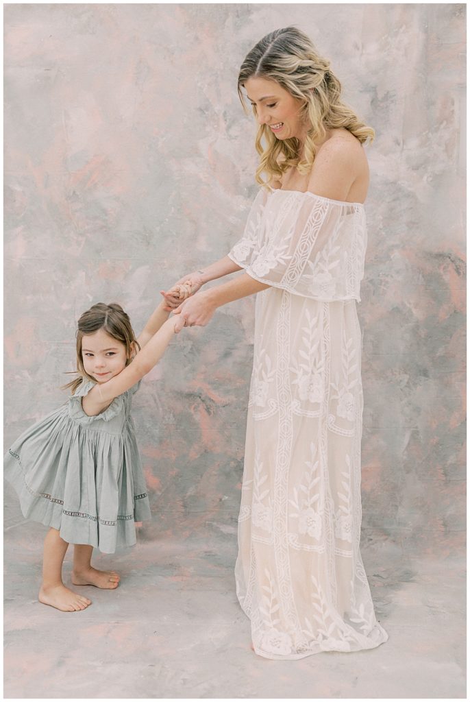 A little girl dances with her mother during their photo session