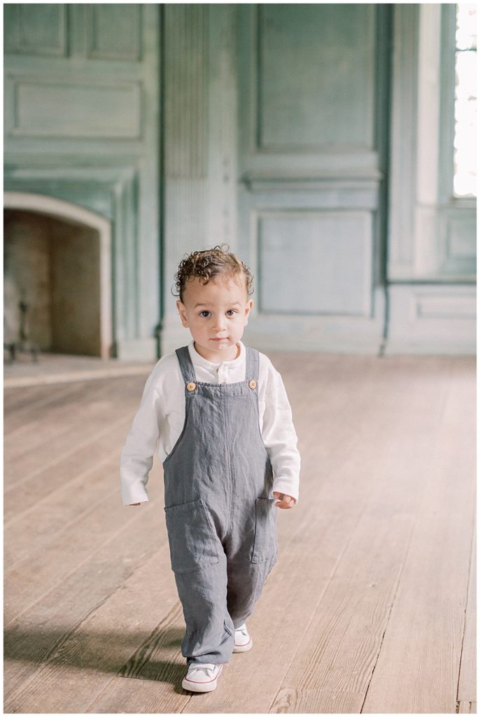 Toddler boy in overalls walks in Salubria manor