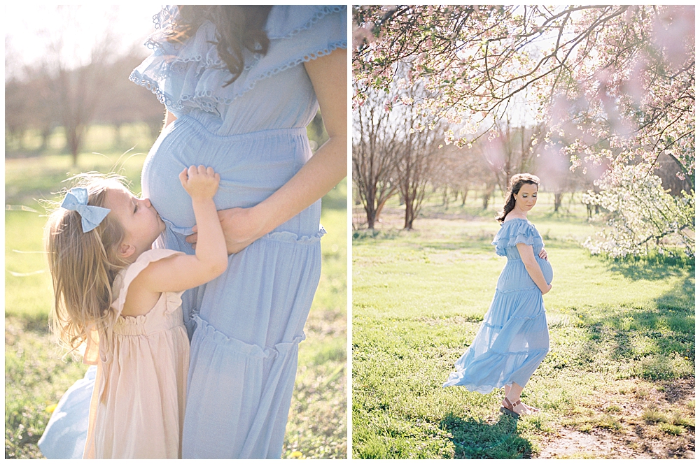A pregnant mom in a blue dress stands with her stand kissing her belly at the National Arboretum