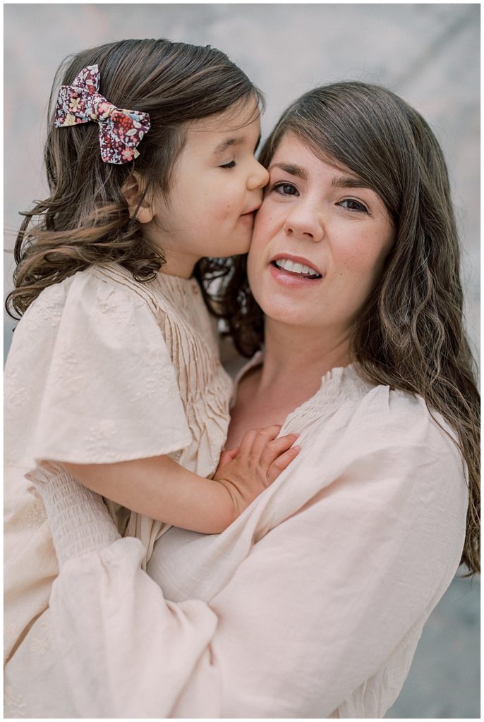 Little girl kisses her mother's cheek