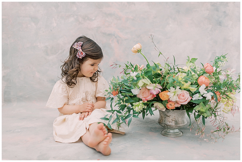 A little girl sits and looks next to a floral display in a photography studio in Washington DC