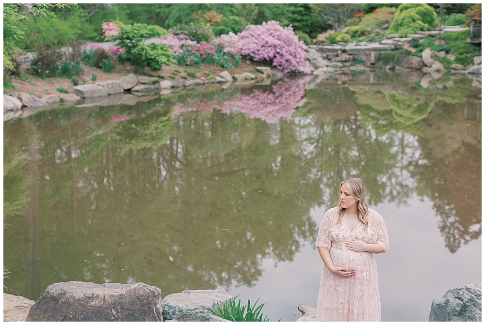 Pregnant woman in pink Needle & Thread dress in front of the pond at Brookside Gardens in Maryland.
