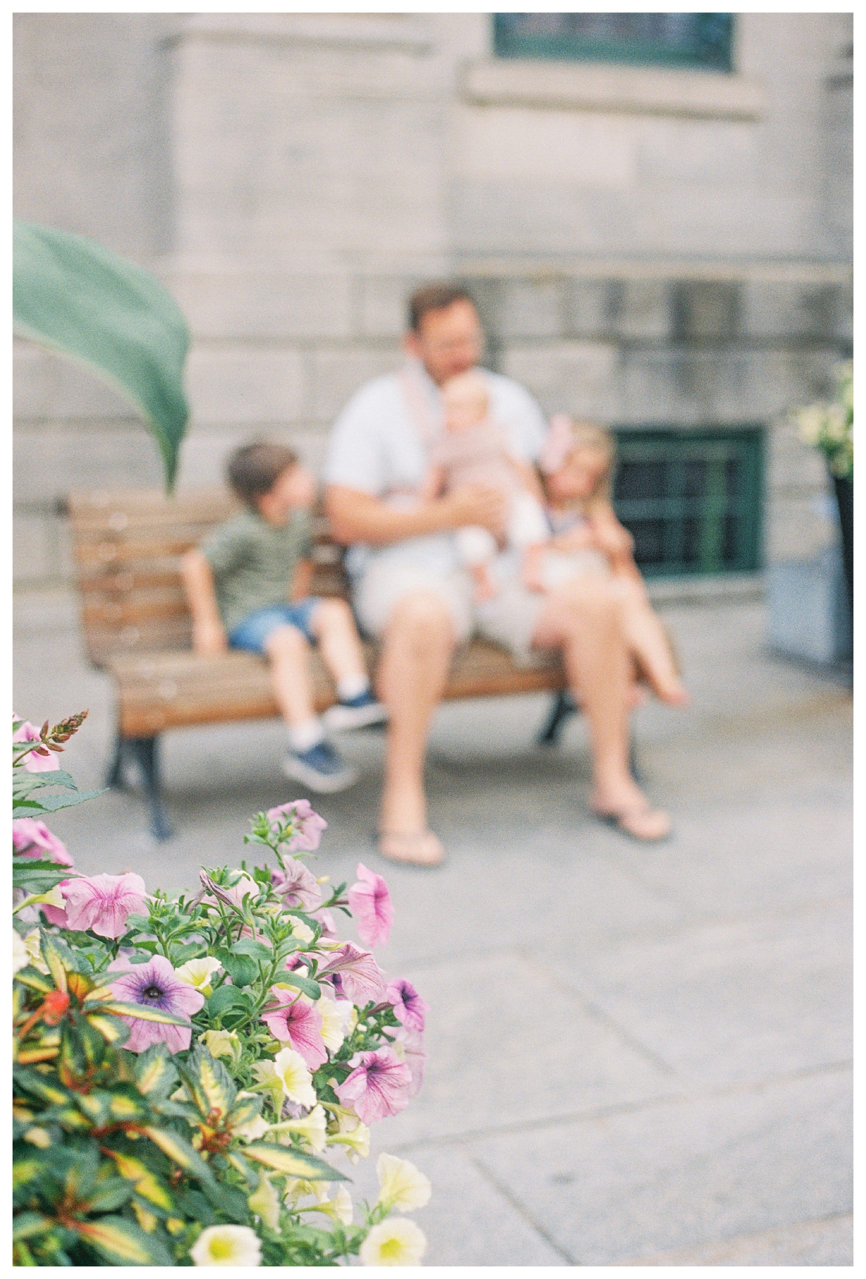Blurry image of father sitting on bench with three children in Old Montreal.