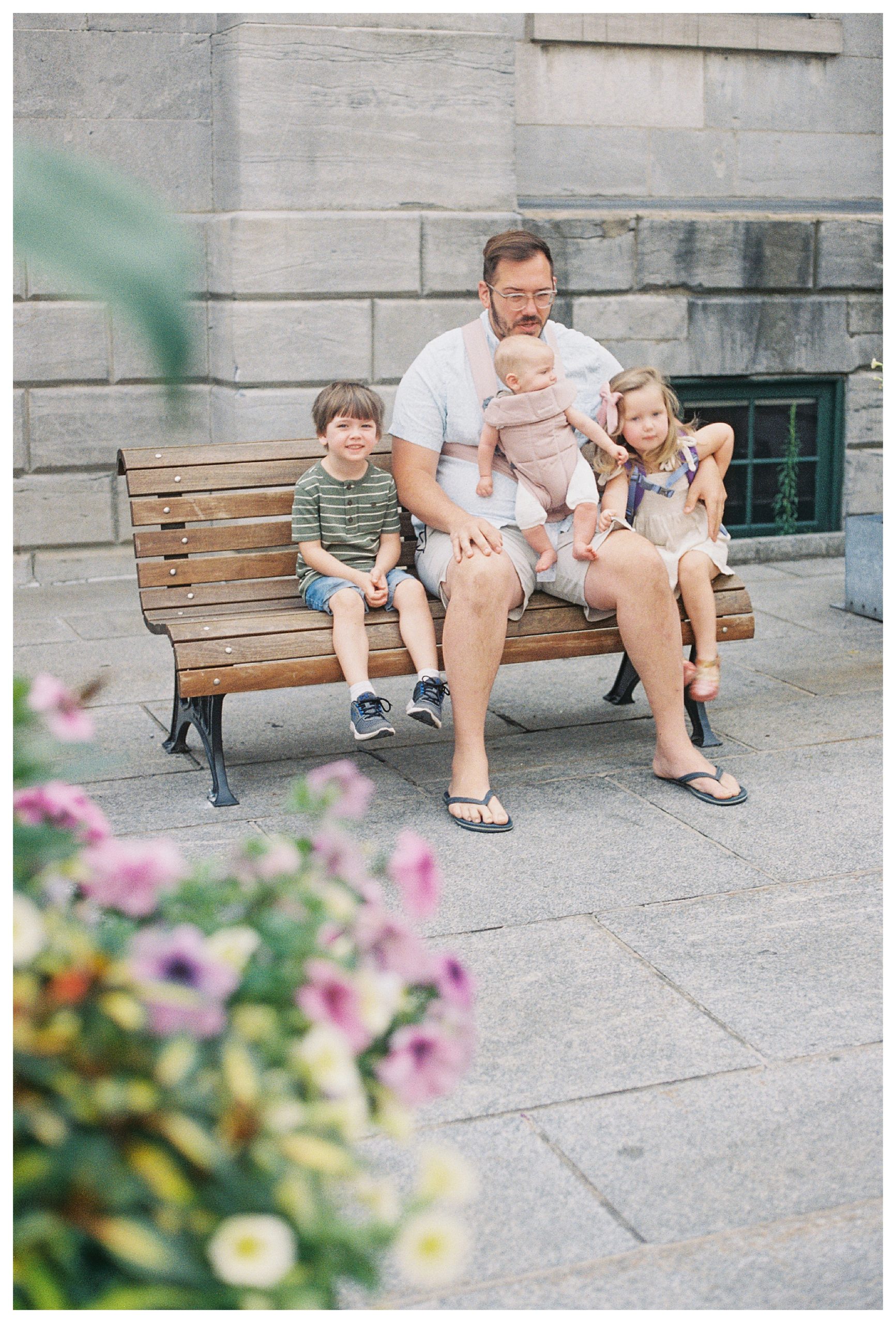 Father sits on bench in Old Montreal with three young children.