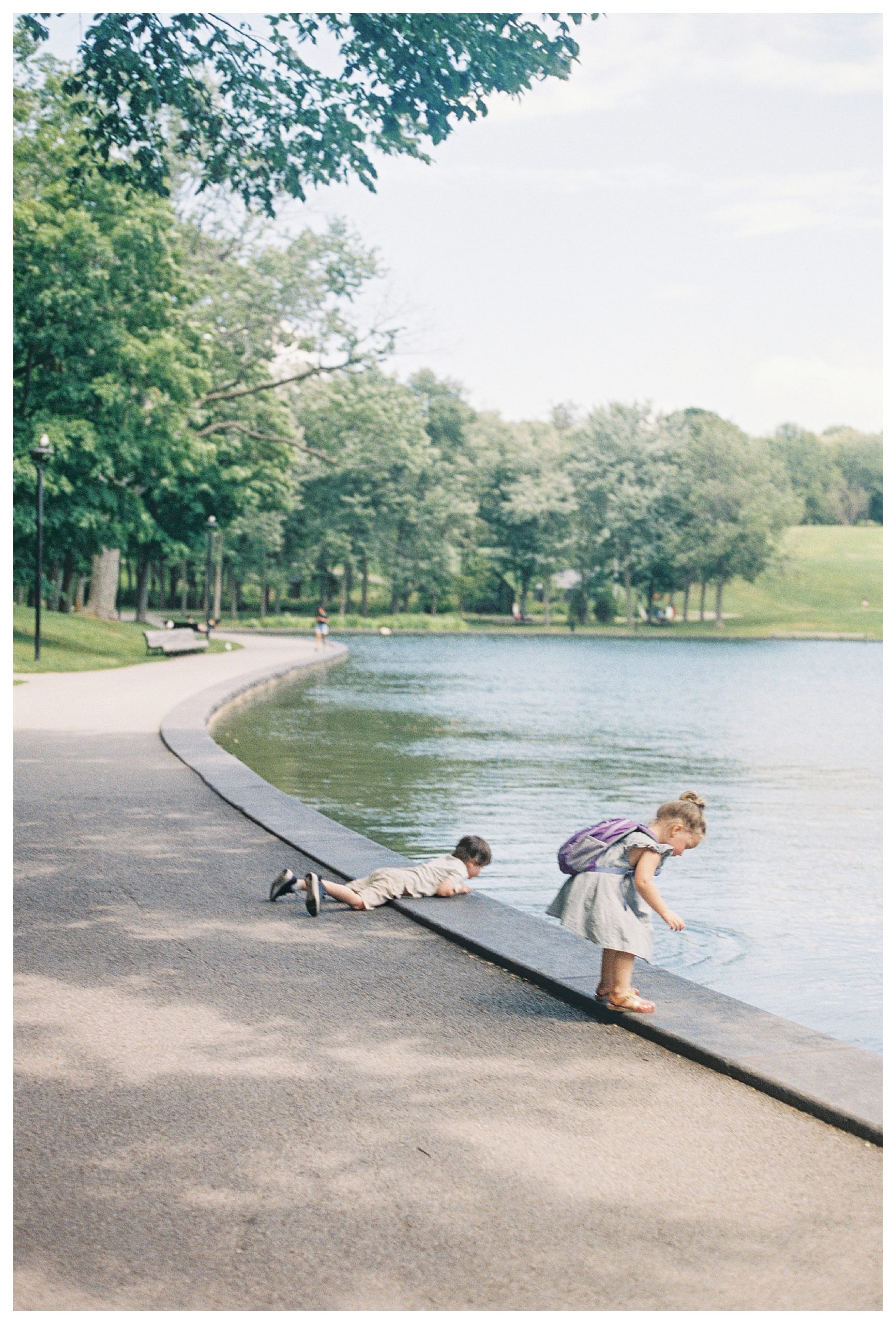 Two young children lean over a lake in   Mont-Royal in Montreal, Canada