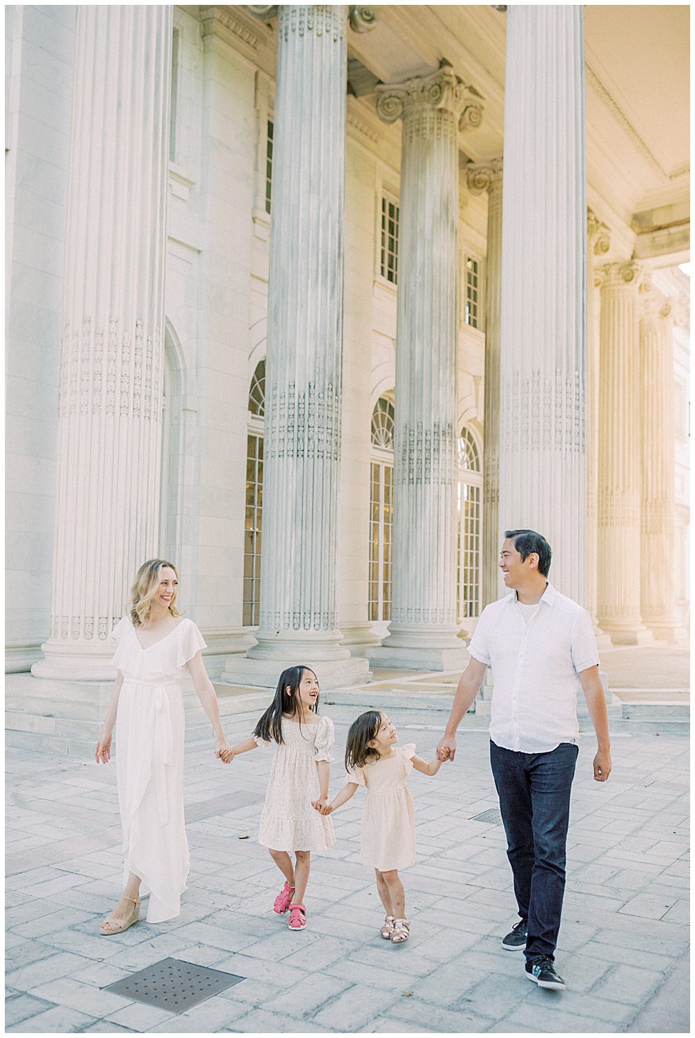 Mother, father, and two young daughters walk together in front of the columns at DAR Constitution Hall.