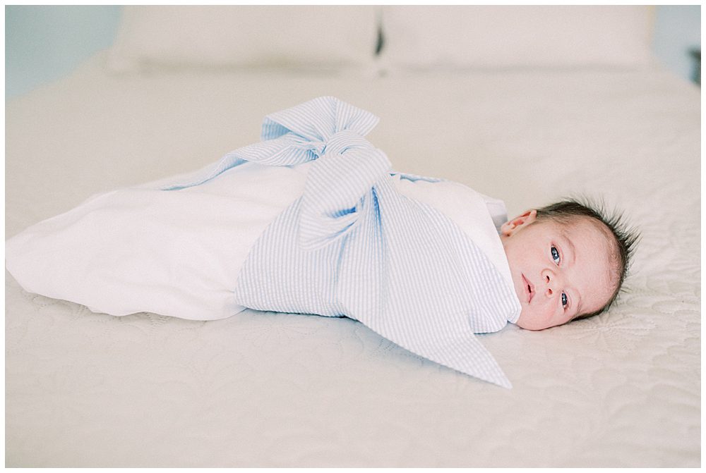Newborn baby boy wrapped in Beaufort Bonnet Company lays on the bed.