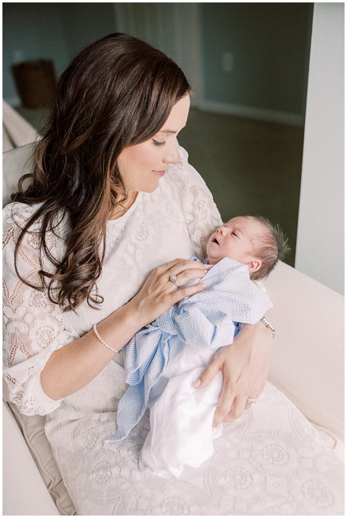 Mother holds her newborn baby boy wrapped in a Beaufort Bonnet Company blue bow swaddle.