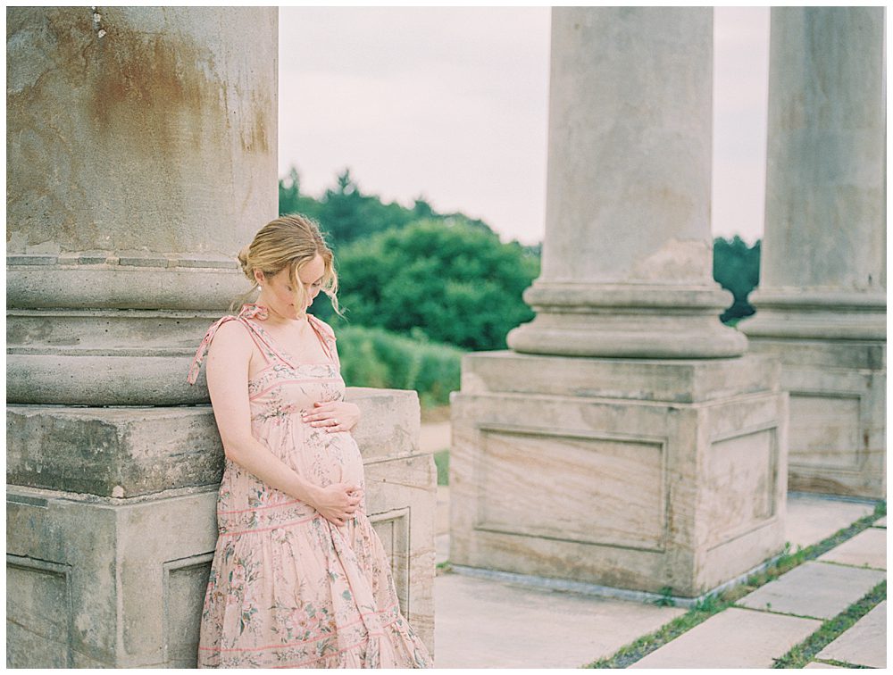 Pregnant blonde woman leans against column during her National Arboretum maternity session.