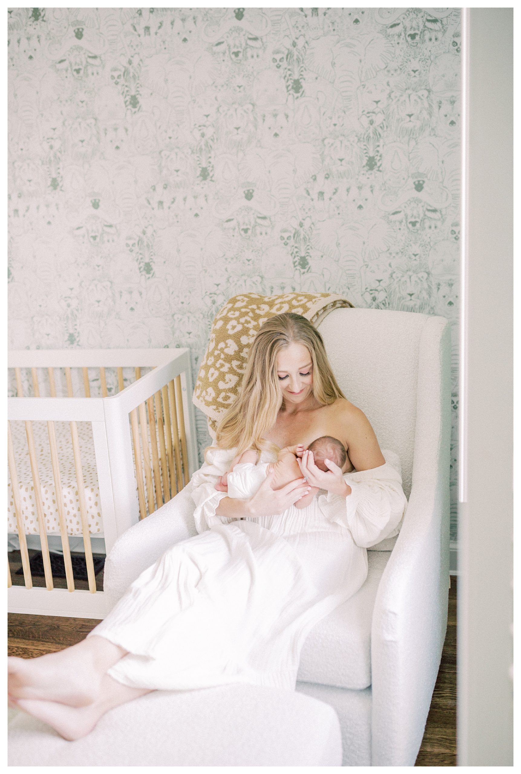 Blonde new mother nurses her newborn baby in the nursery during their DC newborn session.