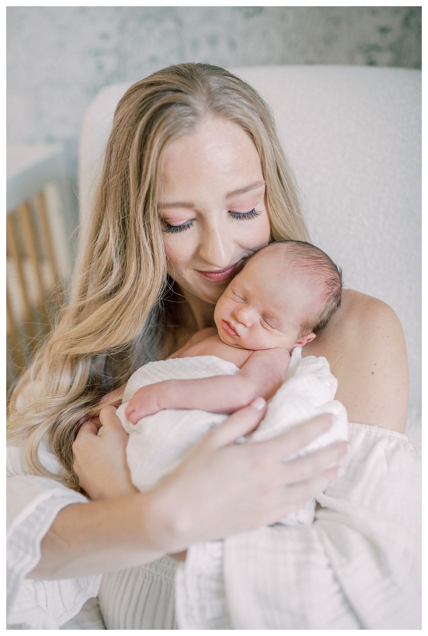Blonde new mother holds her baby up to her face during her DC newborn session.