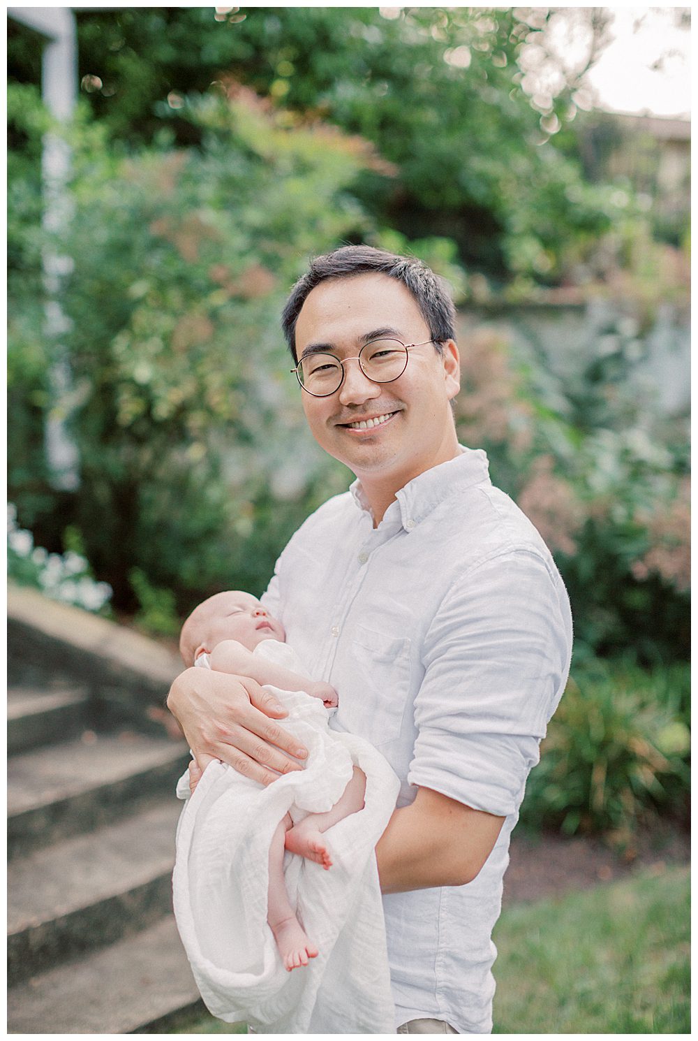 Dad smiles while holding newborn daughter outside during Alexandria VA newborn session.