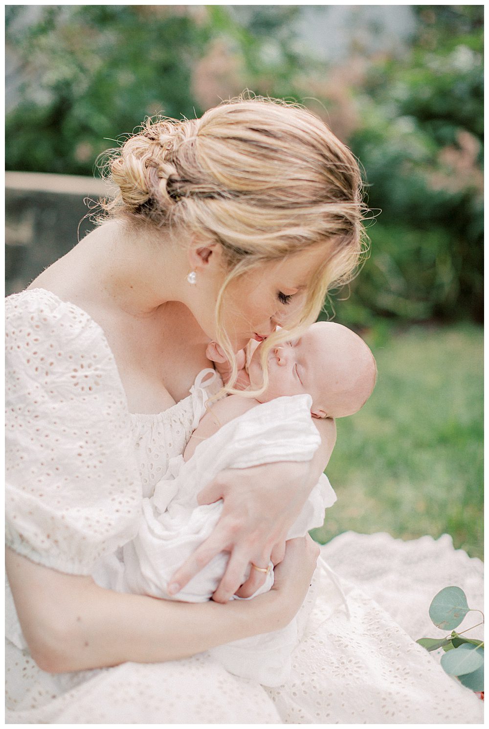 Blonde mother holds up newborn baby up to kiss on the cheek during Alexandria VA newborn session. 