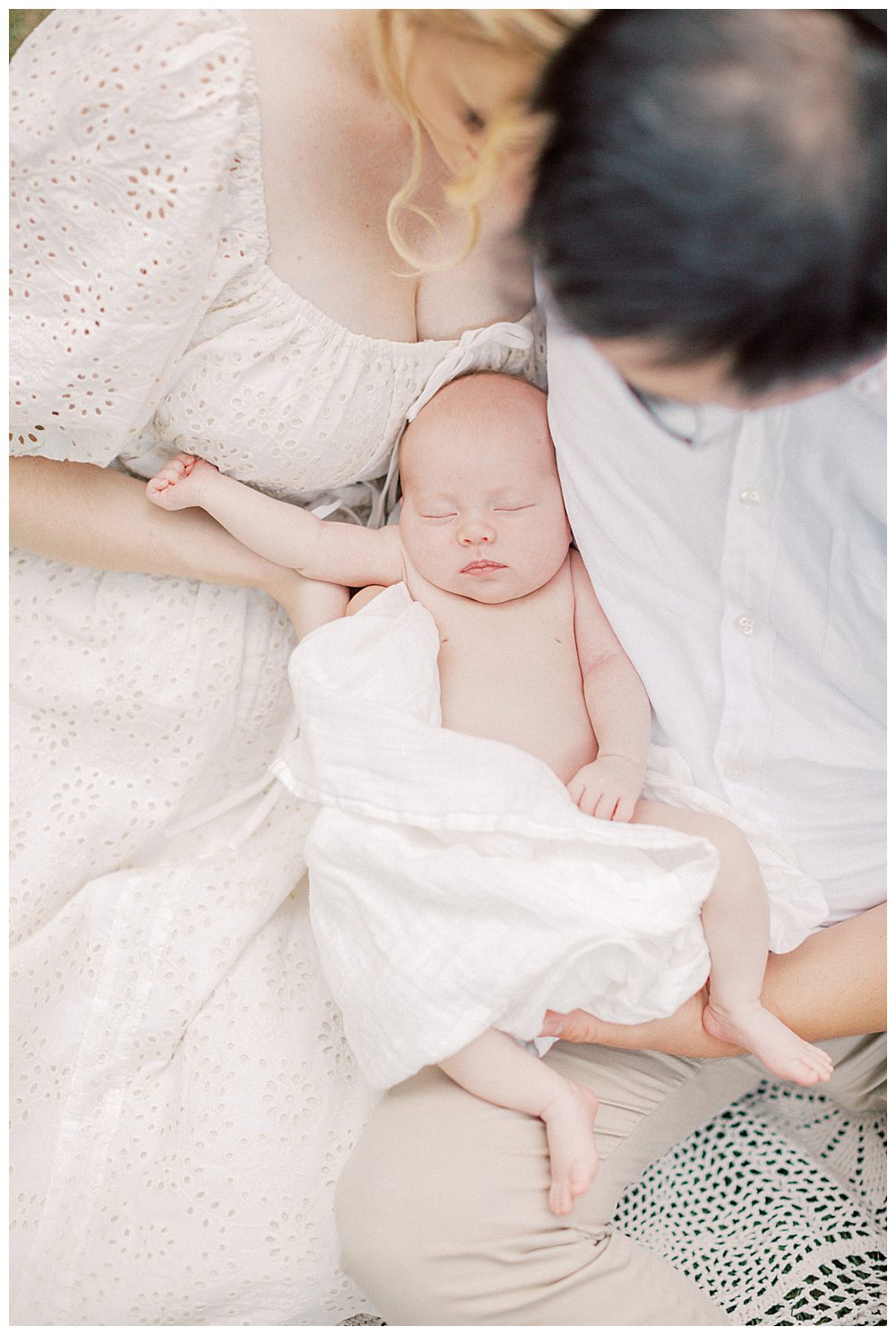 Newborn baby girl sleeps in the arms of her mother and father during Alexandria VA newborn session.