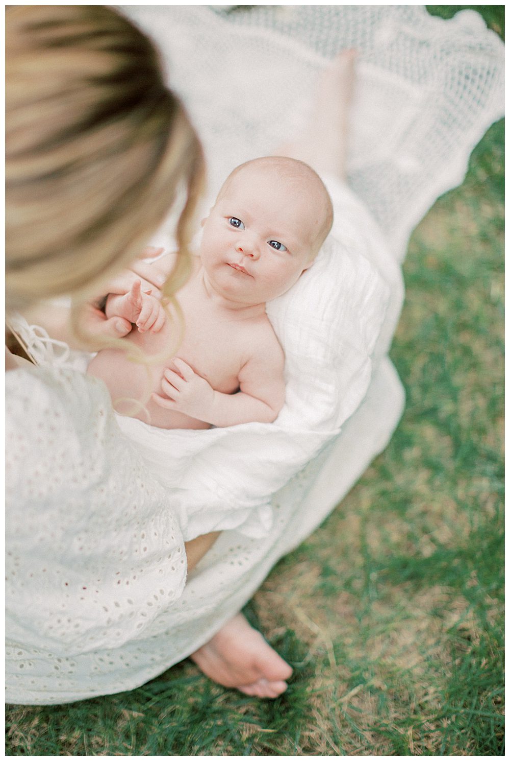 Newborn baby girl looks up at her mother during their outdoor newborn session.