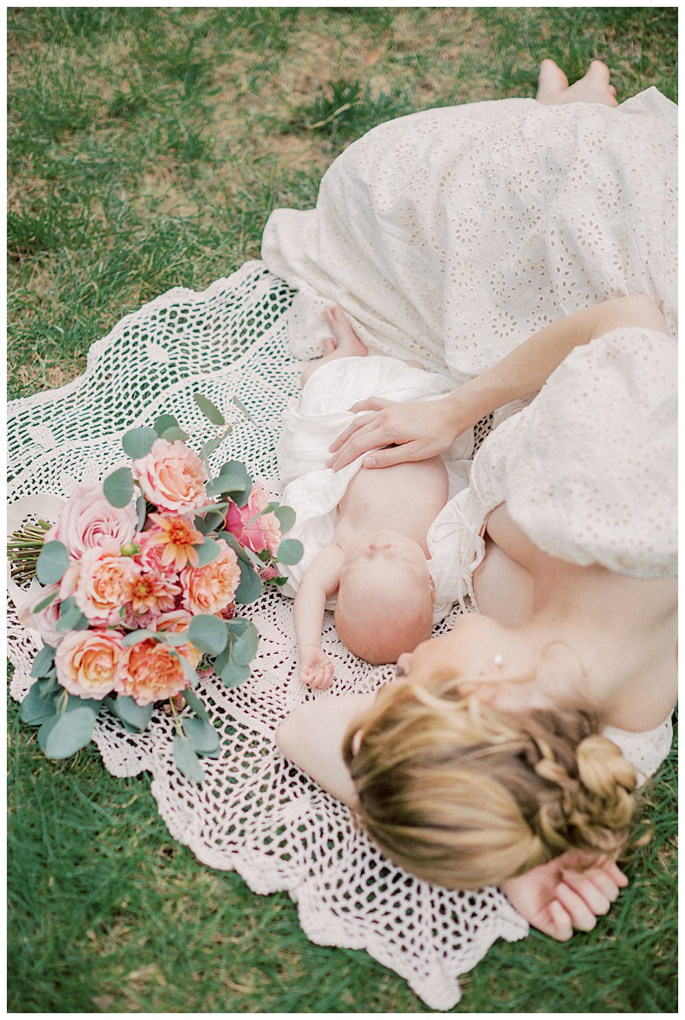 New mother lays on crochet white blanket outside next to her newborn baby and bouquet of roses during outdoor newborn session in Alexandria, VA.