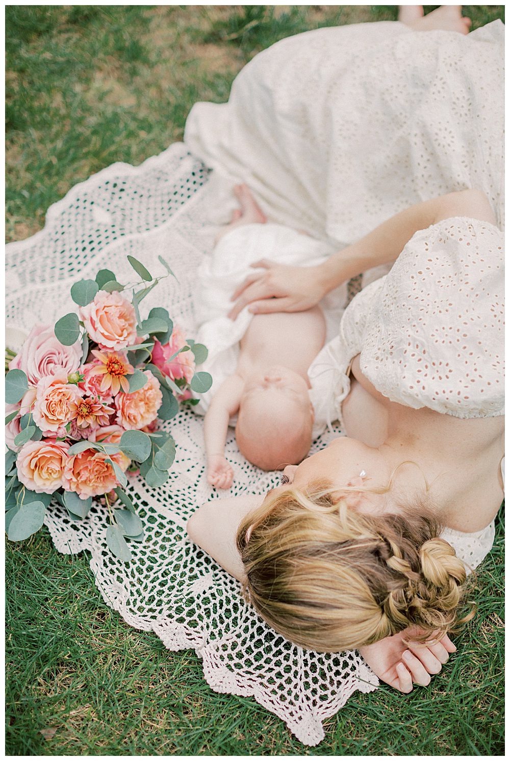 Blonde mother lays on crotchet blanket with newborn baby and roses.