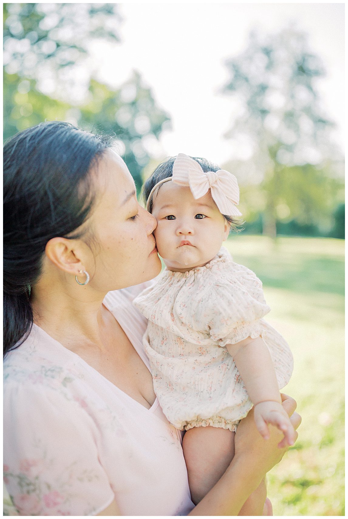 Mother kisses her infant daughter's cheek during her family photo session.