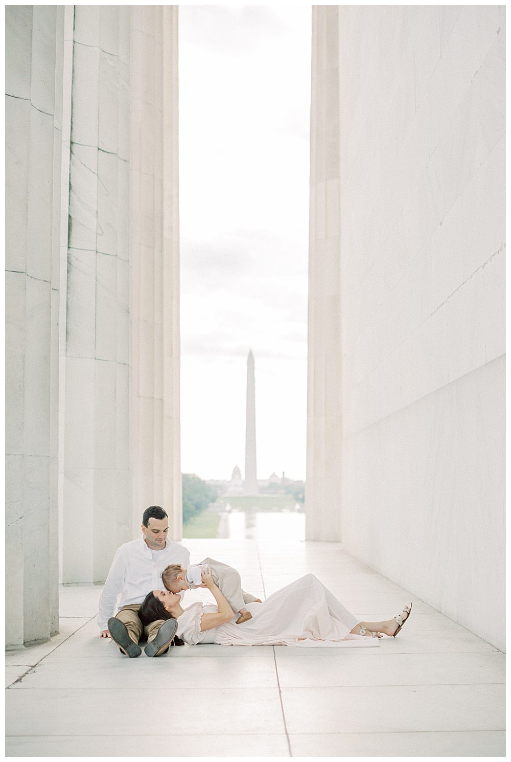 Mother kisses son's head while holding him as she lays in husband's lap during DC Monuments Family Photo Session.