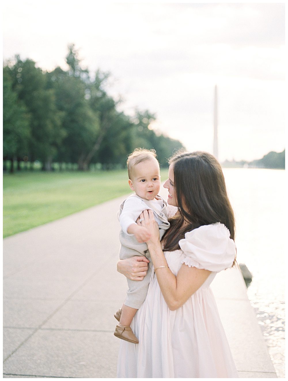 Mother smiles while holding her toddler son during DC Monuments Family Photo Session.