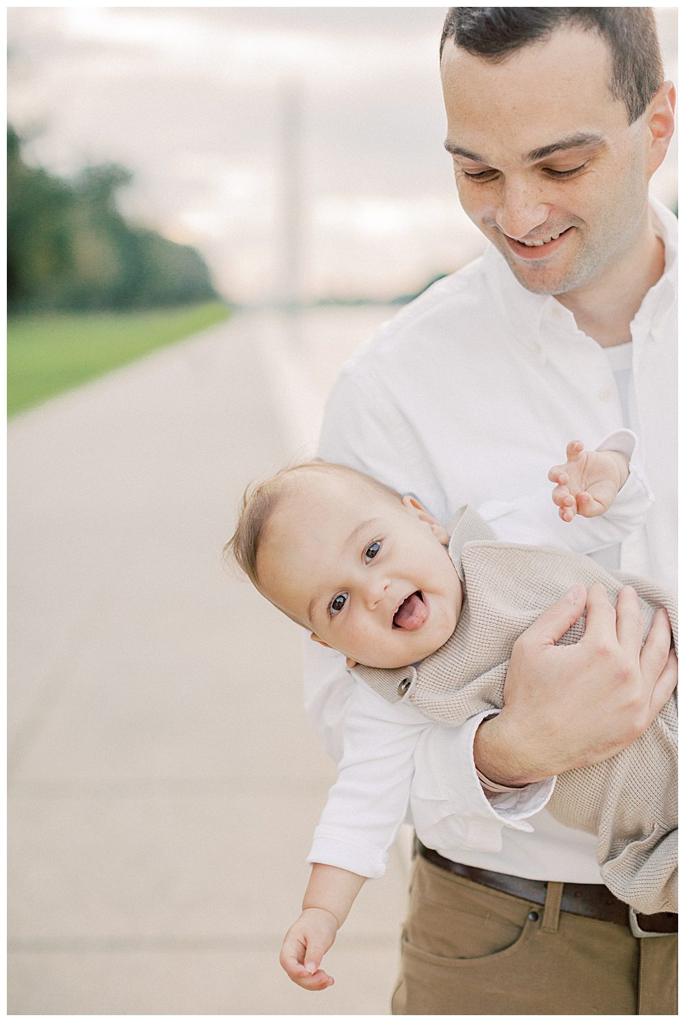 Toddler boy smiles while being held sideways by father during DC Monuments Family Photo Session.