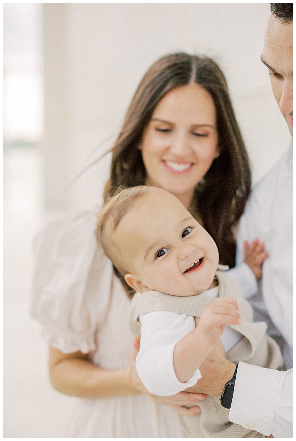 Little boy smiles while parents hold him during their Washington DC photo session.
