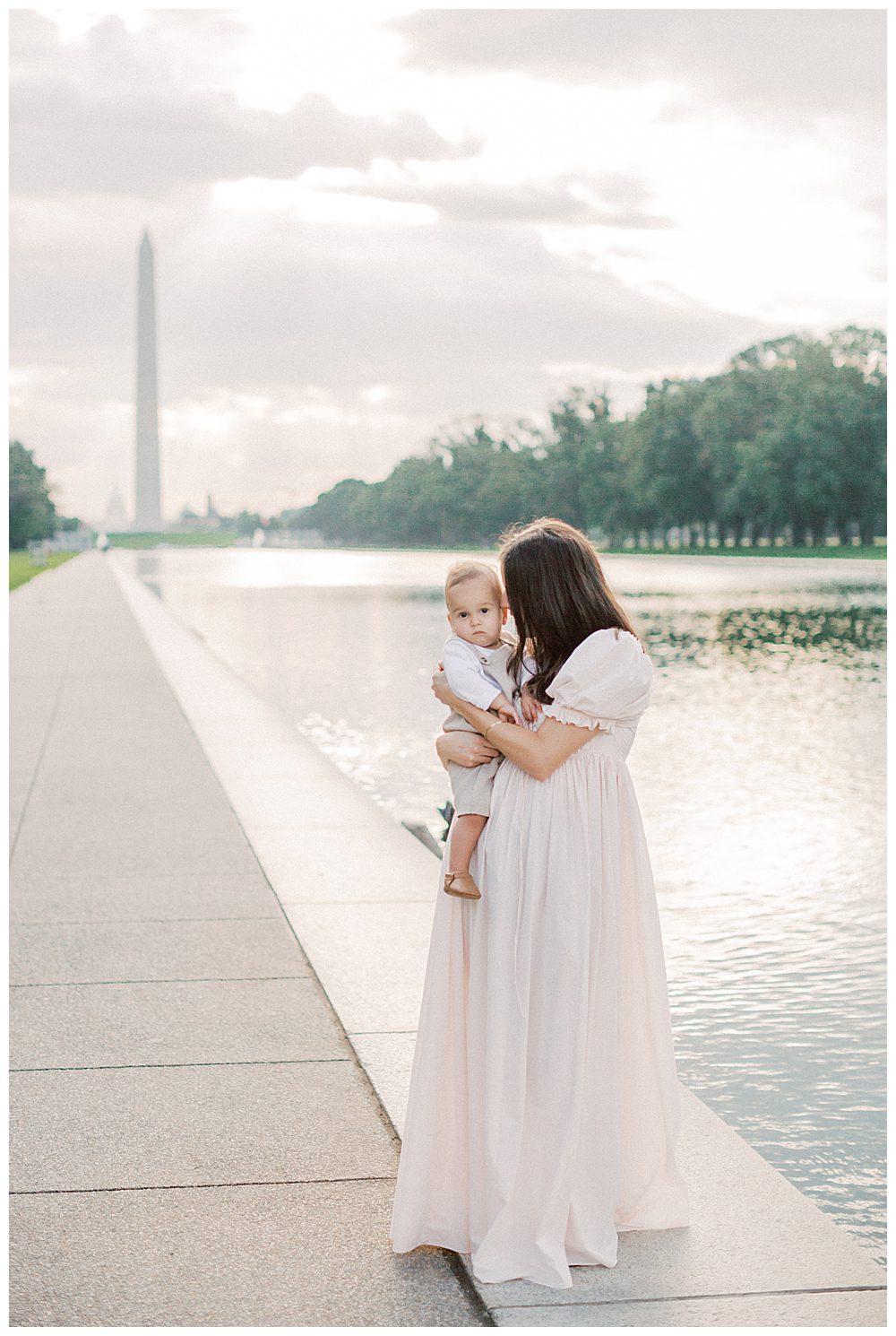 Mother leans into toddler son at reflecting pool during DC Monuments Family Photo Session.