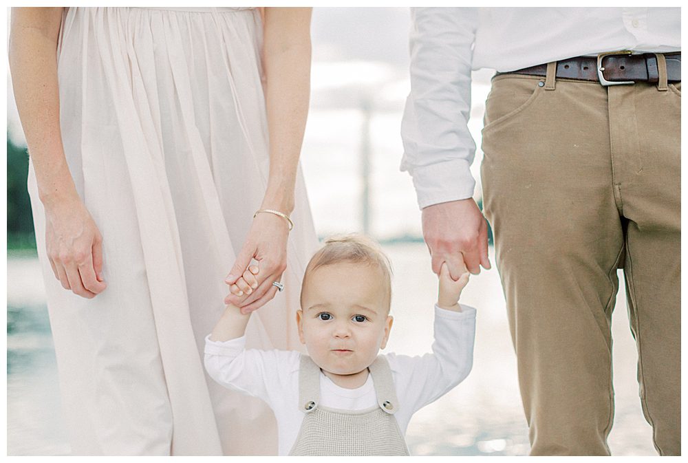 Little boy looks at camera while holding hands of parents during DC Monuments Family Photo Session.