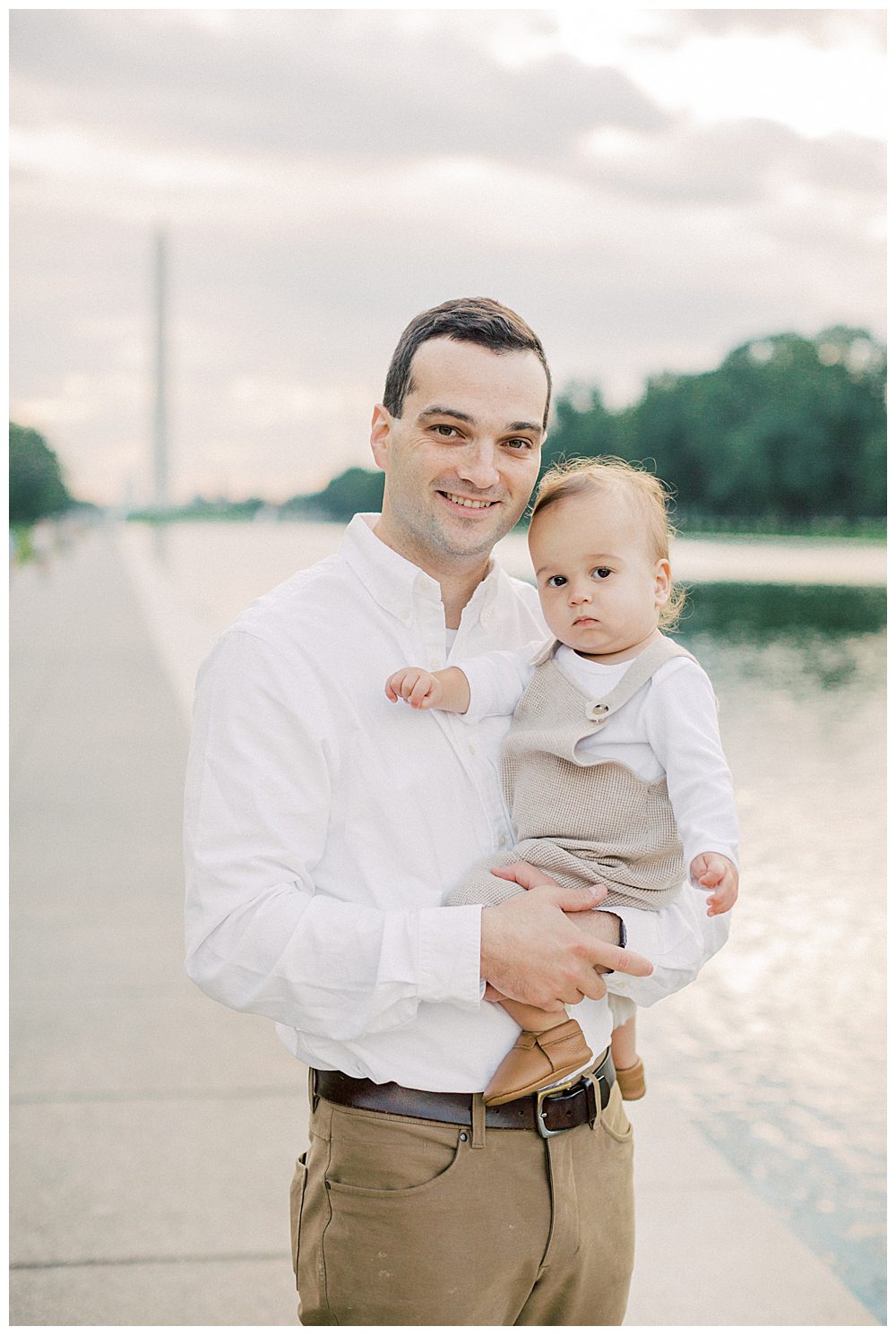 Father holds toddler son and smiles during DC family photo session.