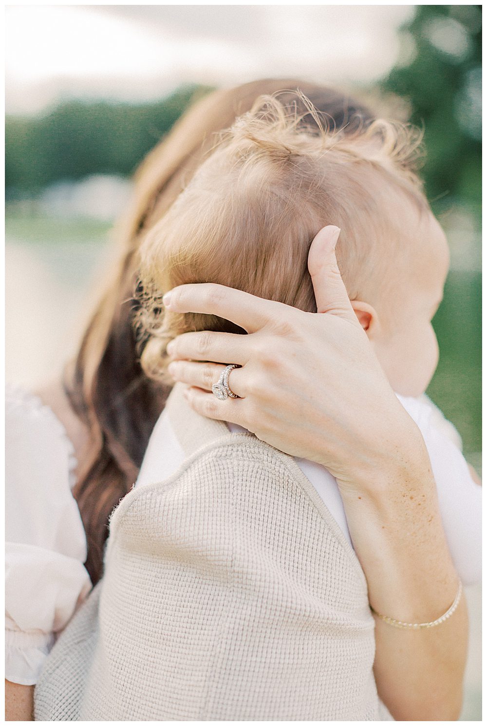Mother wraps hand around toddler boy's head.