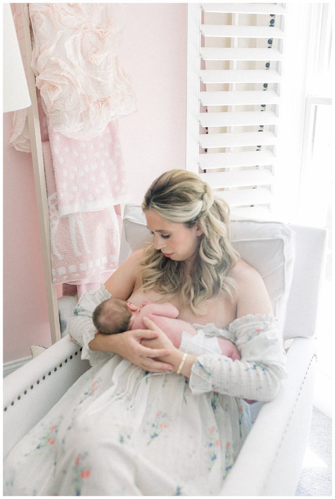 Blonde new mother in Doen Bijou Painted Floral dress nurses her newborn baby girl.