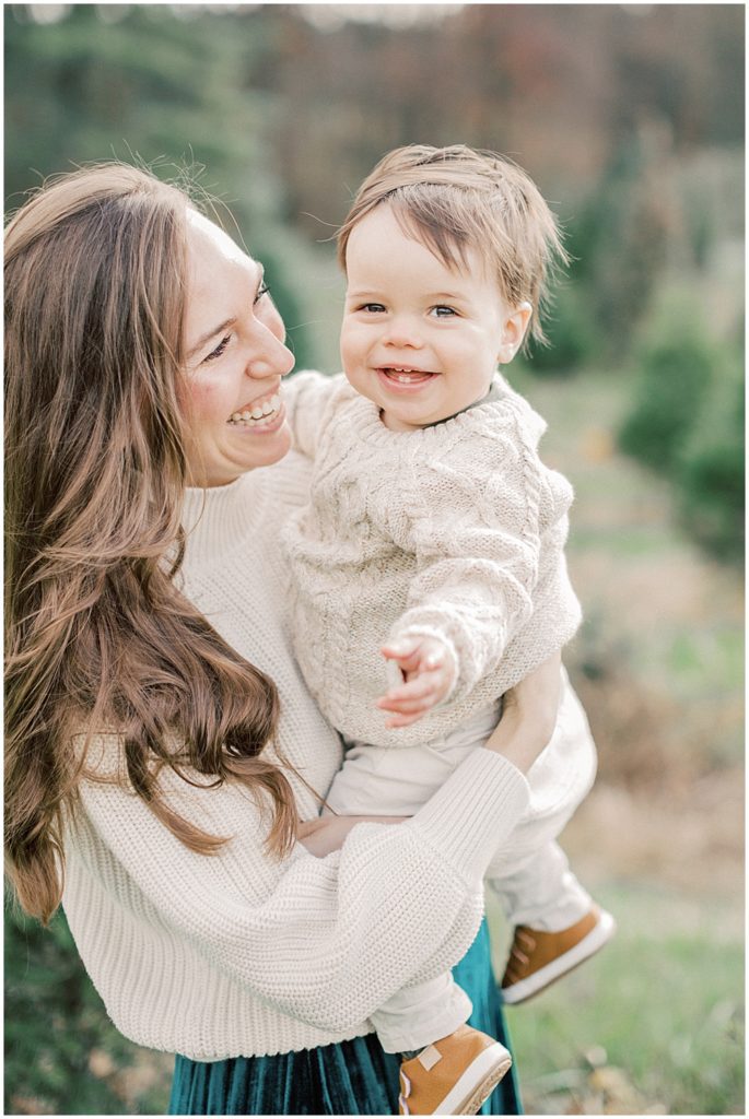 Mother laughs while holding son during Christmas mini sessions at Butler's Orchard.