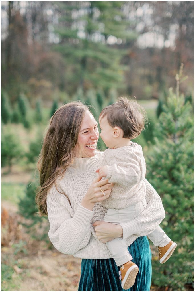 Mother smiles at son at Christmas tree farm.